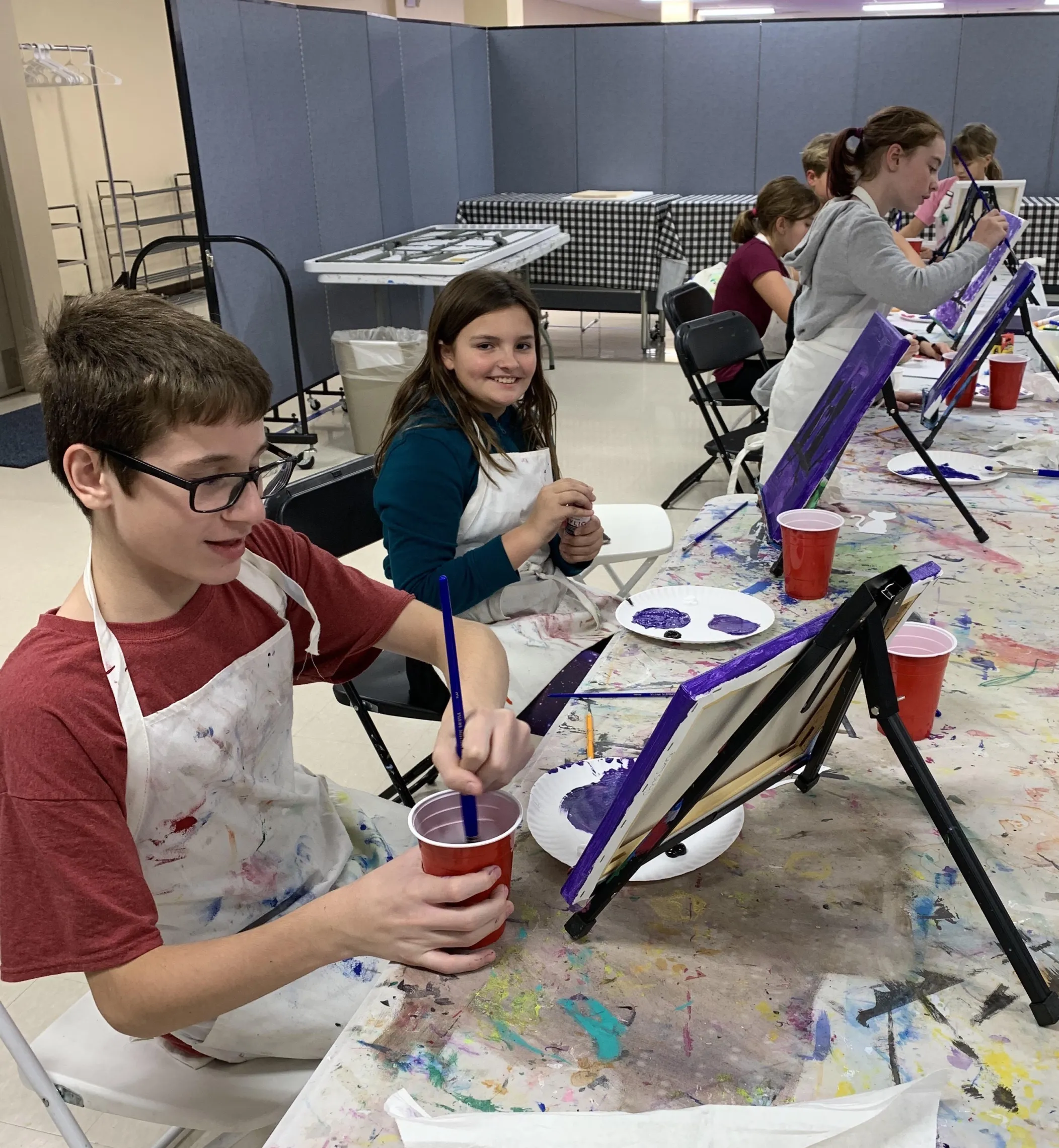 boy painting at table easle
