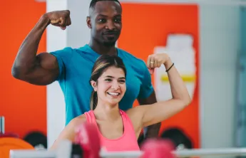 woman shows muscle with personal trainer