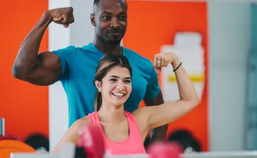 woman shows muscle with personal trainer